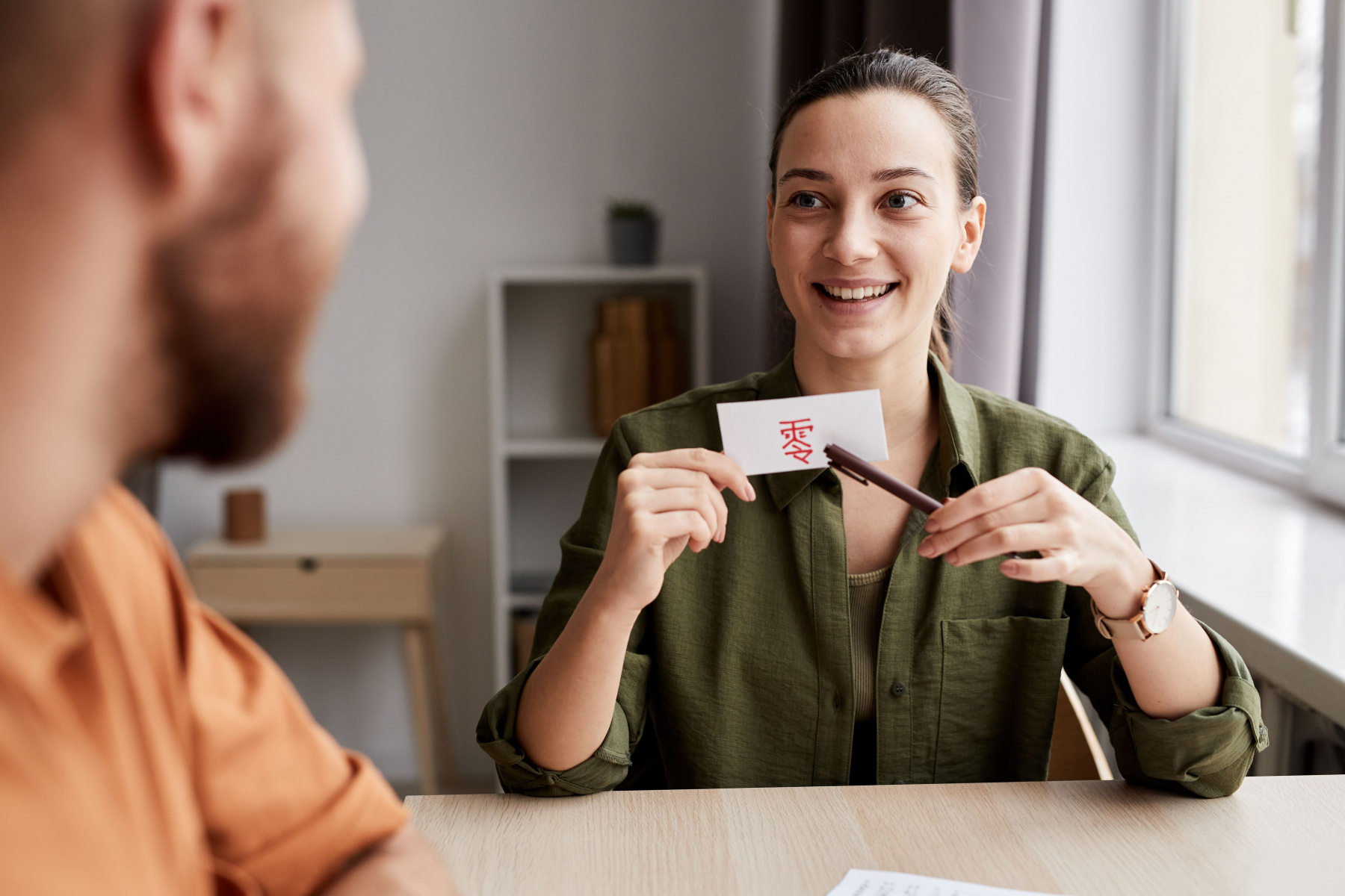 young-smiling-female-tutor-pointing-at-paper-card-2022-12-01-05-29-46-utc.jpg